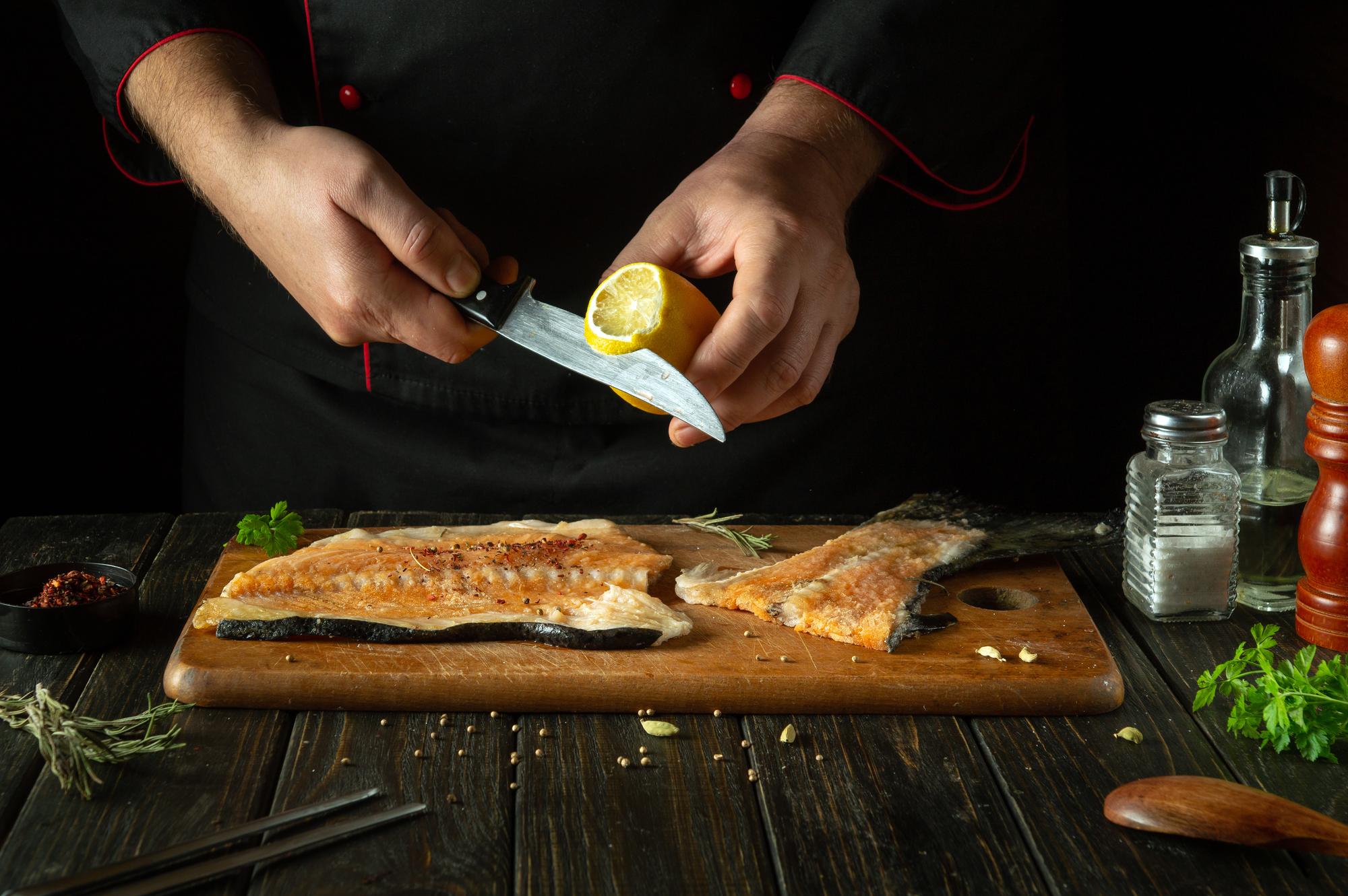 Chef slicing smoked fish in professional kitchen